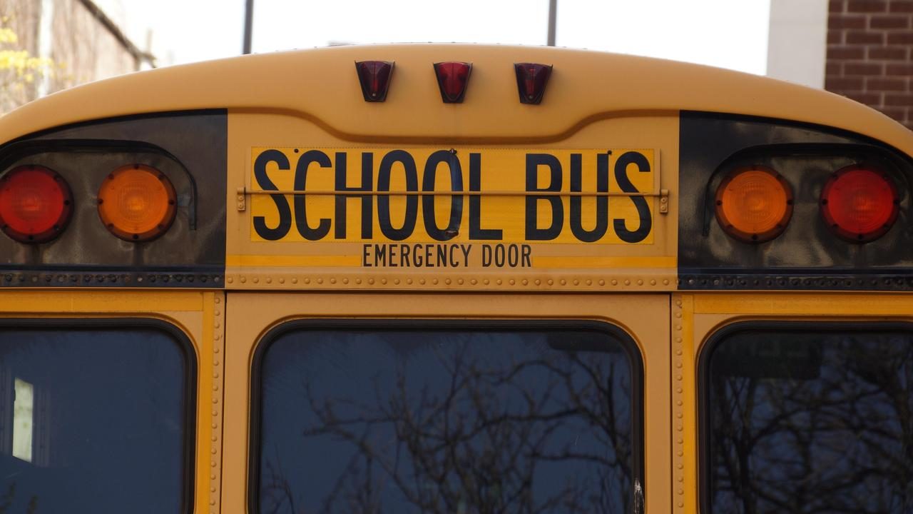 The back of a yellow school bus marked School Bus and Emergency Door